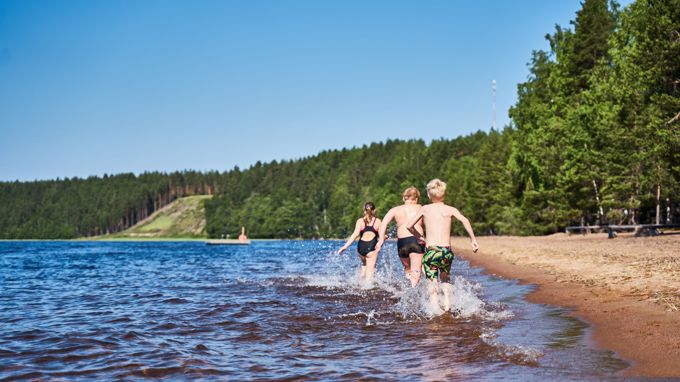 Lapset juoksevat rantavedessä Huuhanrannalla